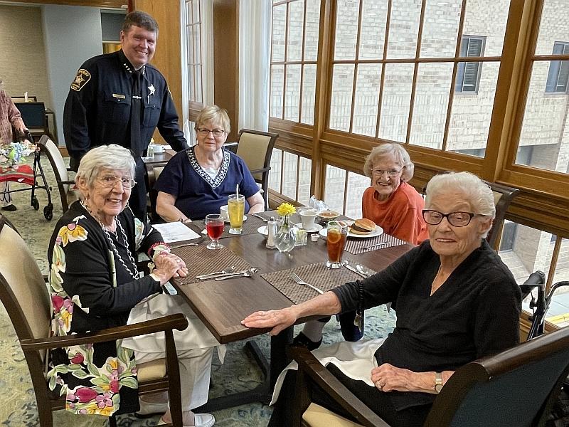 sheriff standing with four seniors seated at dining table for lunch