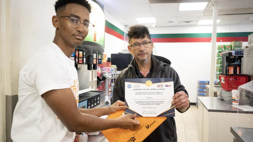 Student presenting 7 Eleven manager a certificate of appreciation