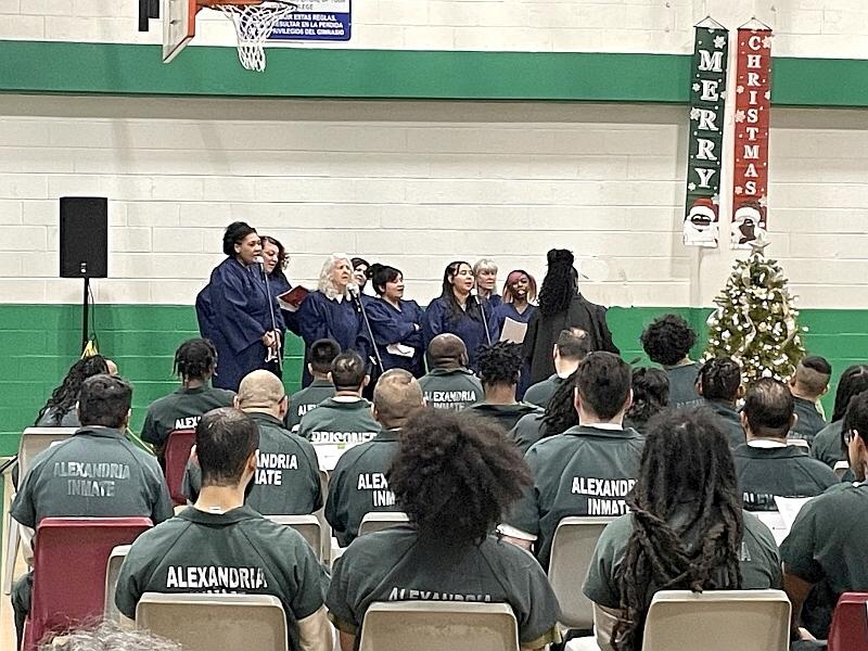 choir members in robes singing and about 20 inmates seated and listening