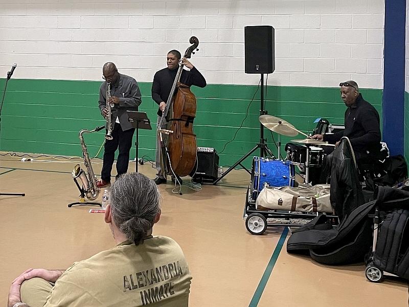three musicians performing as an inmate listens