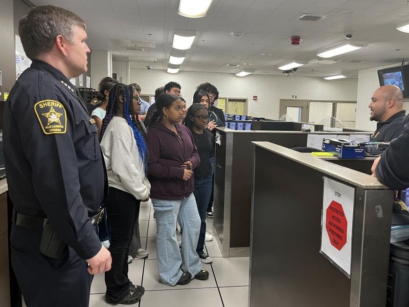 Sheriff and several high school students listening to a deputy talking inside a jail