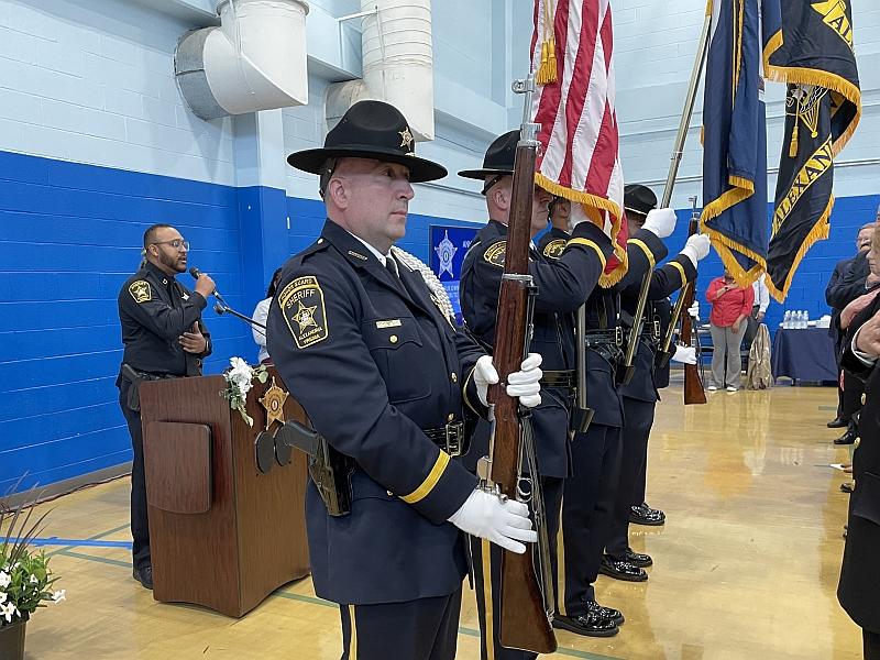 deputy at podium singing with honor guard presenting flags