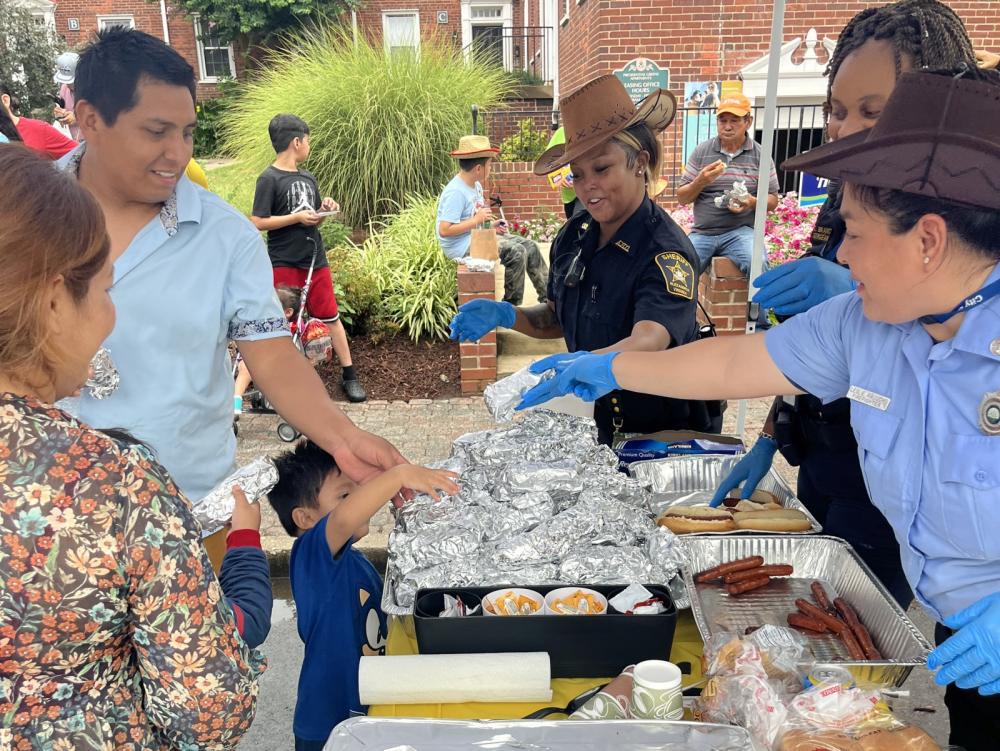 Community event with a family and public safety personnel sharing food wrapped in foil