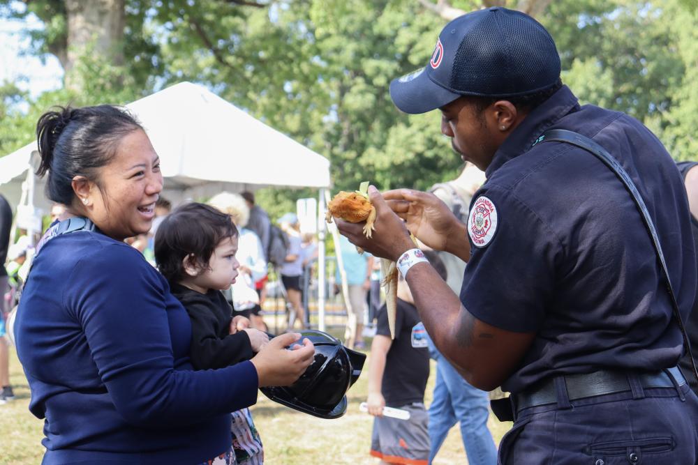 Firefighter showing a bearded dragon to a parent and child