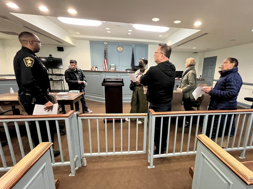 Deputy in blue uniform speaking with several civilians in a courtroom