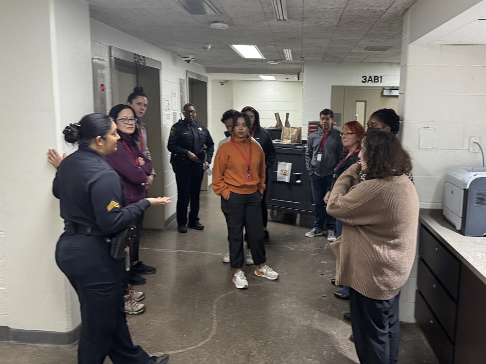 Sheriff's sergeant in a blue uniform giving a tour of the jail to several civilians
