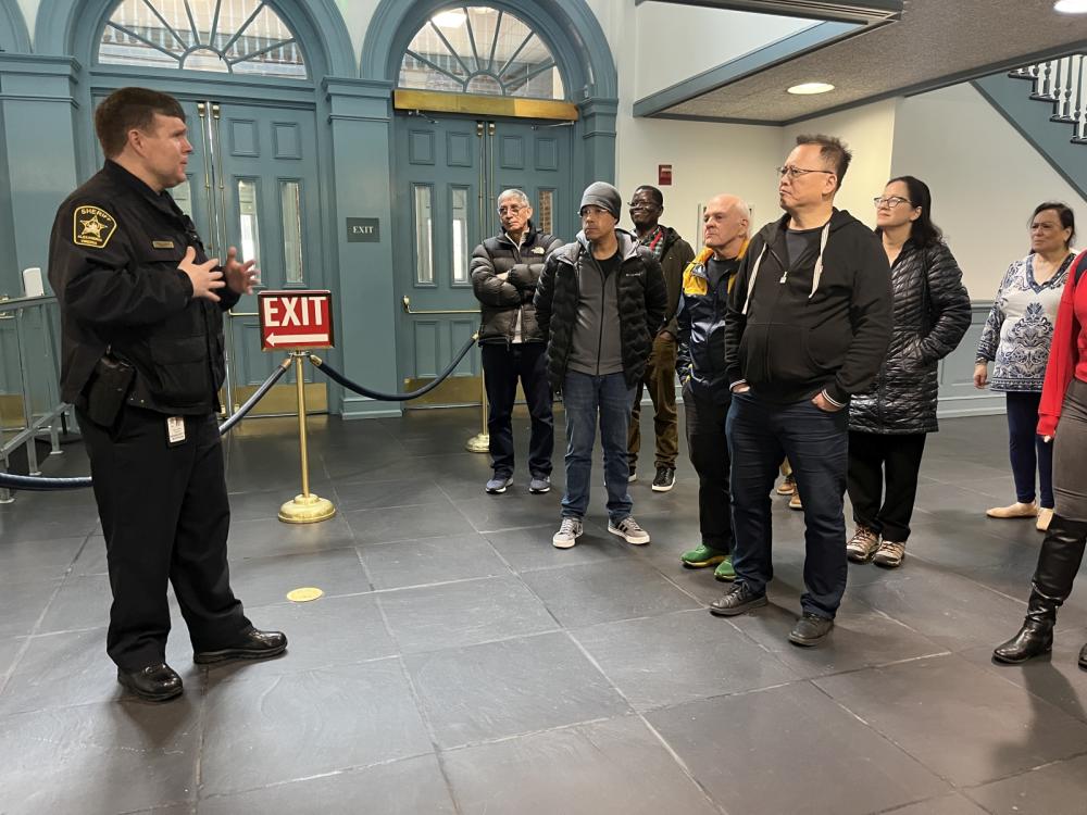 Sheriff in blue uniform welcoming a group of civilians to the courthouse