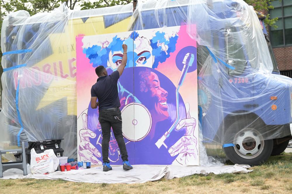 An artist spray paints a mural. 