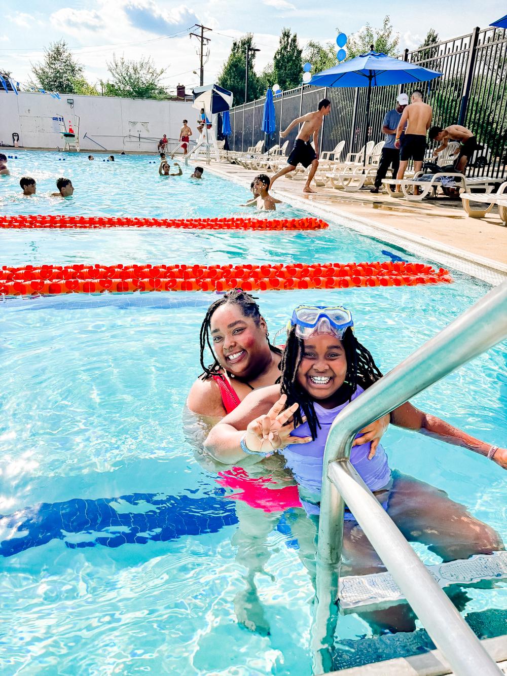 Image of two teens in a pool smiling at the camera