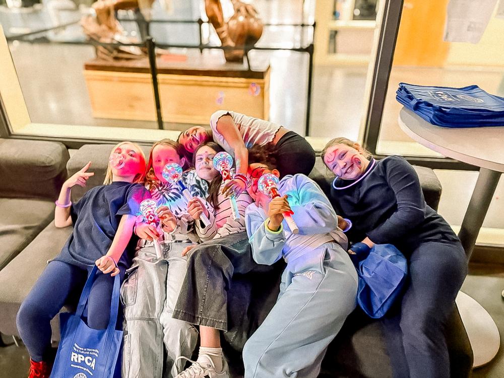 Group of teens huddled on the couch with lit up mics