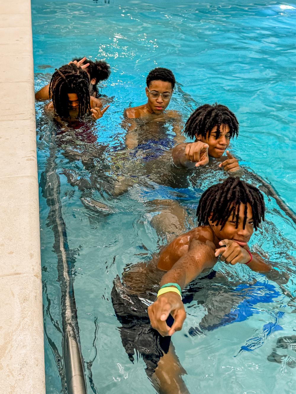 Teenage boys in an indoor pool smiling and posing for the camera