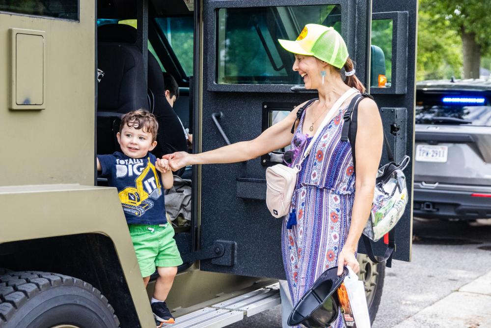 A woman and child step out of a police armored vehicle
