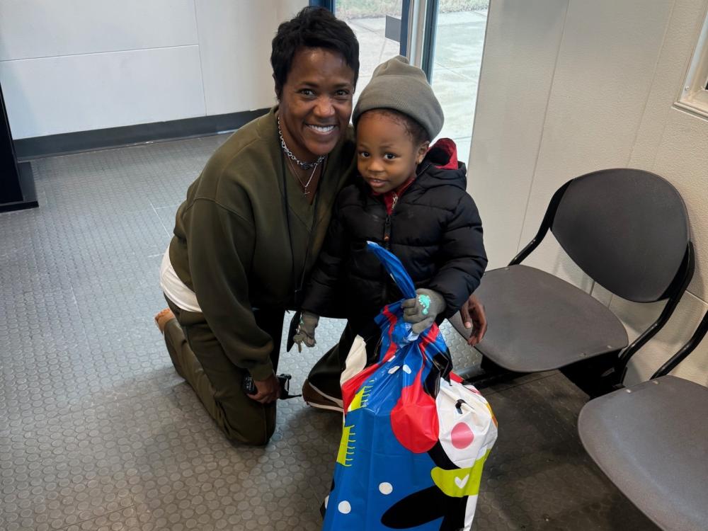 Civilian staff member with small child and holiday gift bag