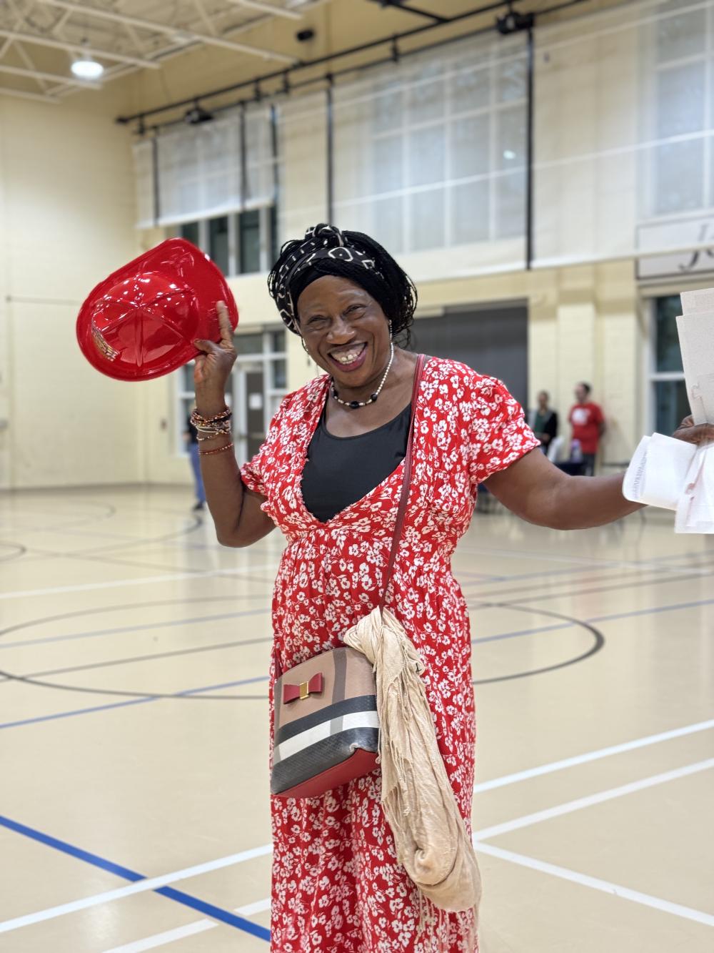 Community member wearing a red dress while holding a red plastic firefighter hat