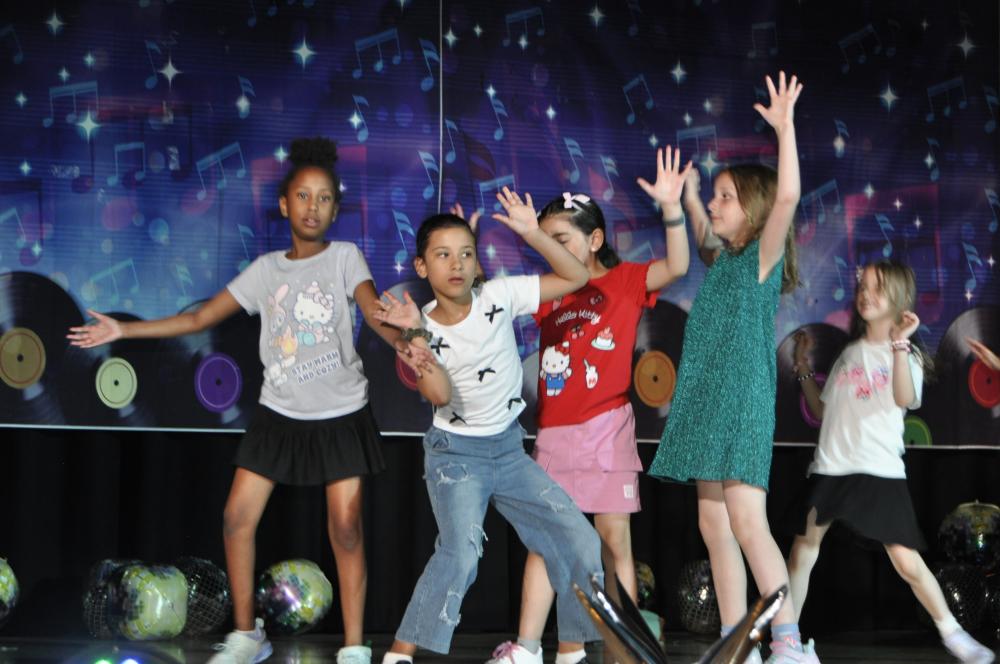 Group of kids wearing casual clothes posing on the stage for Night of Stars