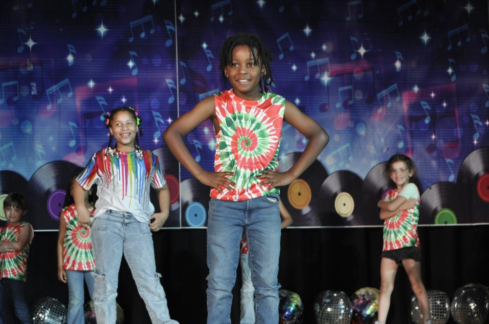 Kids in tie dye smiling on stage
