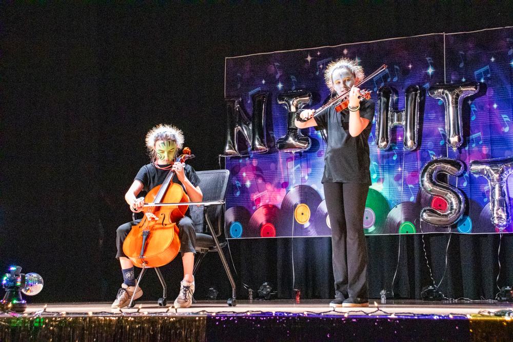 Performers in black costumes playing the cello and violin