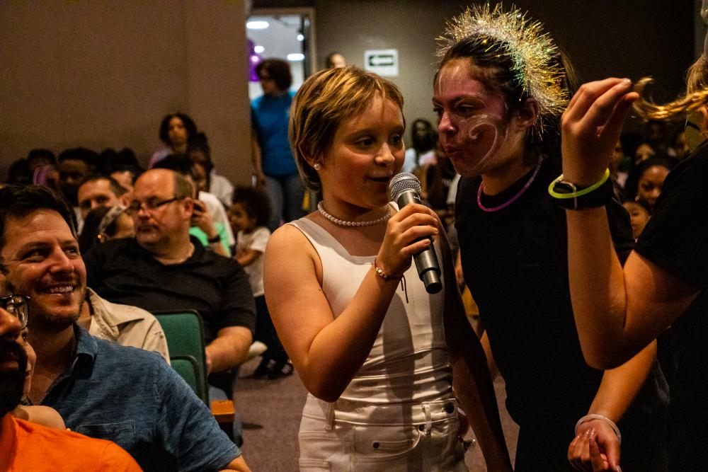 Performers holding a mic while standing among the crowd