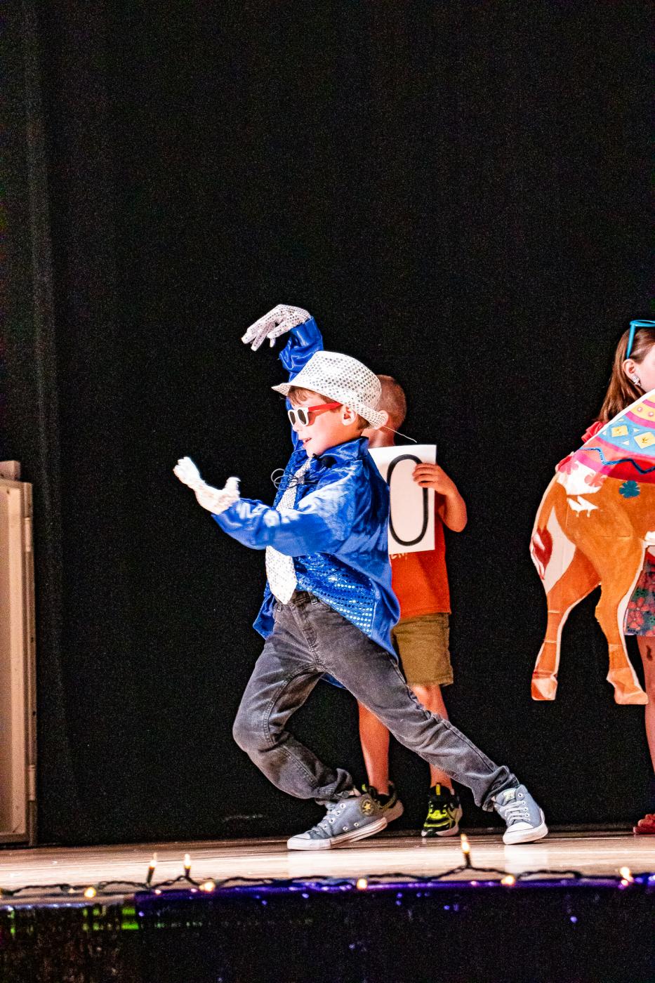 Performer in blue sparkly jacket and a silver sparkly hat and white gloves