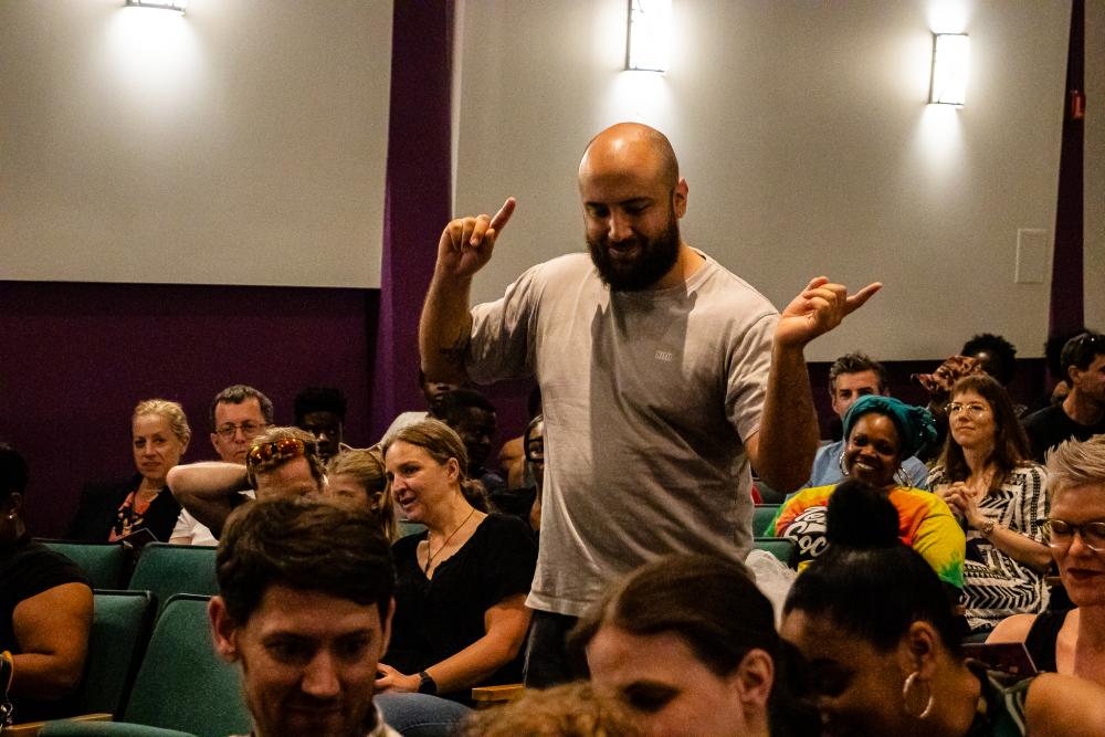A man is standing among the seated crowd dancing
