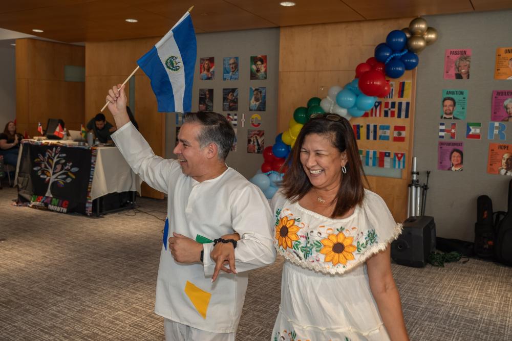 woman and man in white and yellow outfits holding a flag