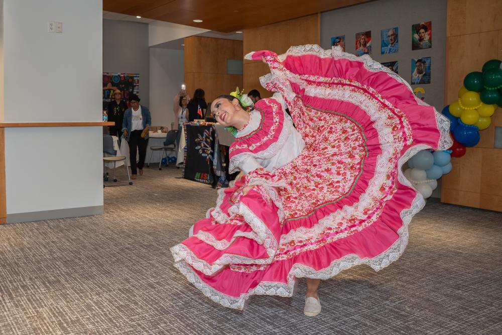 Room with pink and white dress dancing in a room with others watching