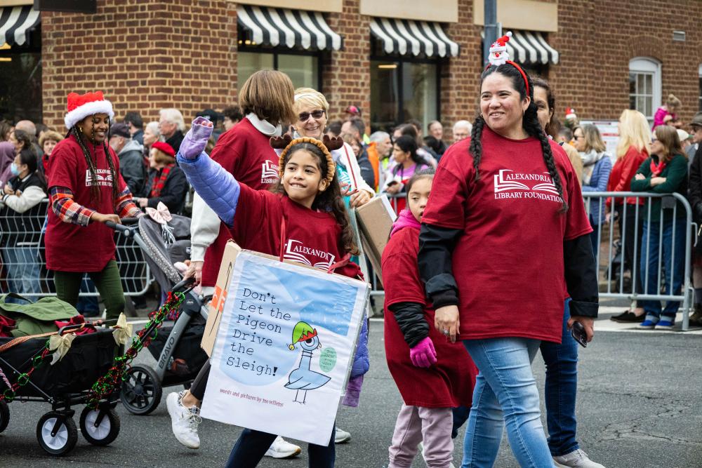 group of six people walking in the parade with red shirts on and a banner