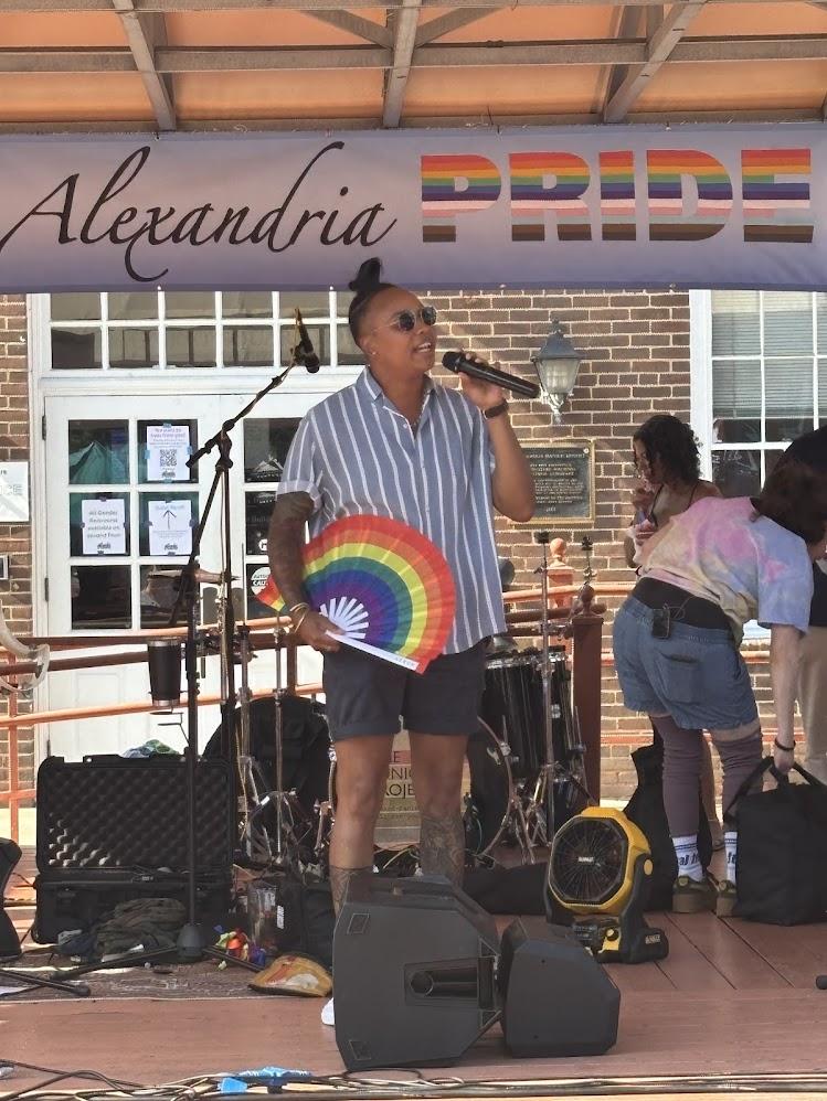 Speaker on stage with rainbow fan at Alexandria Pride 2025