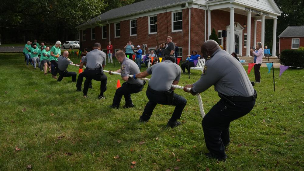 APD officers pull together during a spirited tug-of-war at Alexandria Free Methodist Church, with community members cheering from the sidelines.