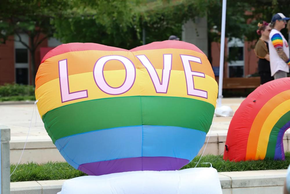 Large inflatable rainbow heart with word "love" printed on it