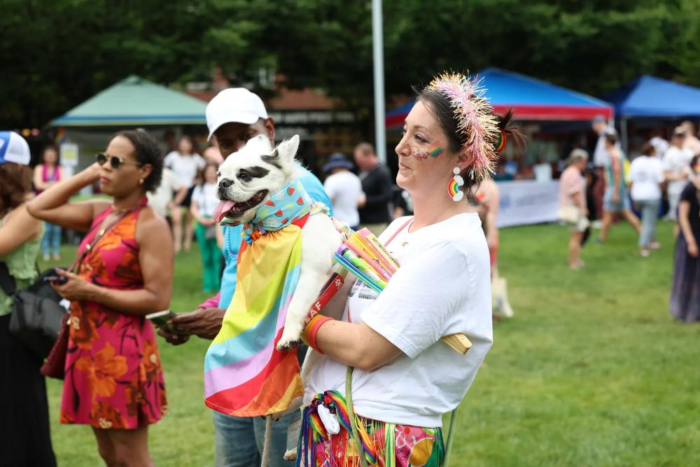 Person holding dog in rainbow attire at Alexandria Pride 2026