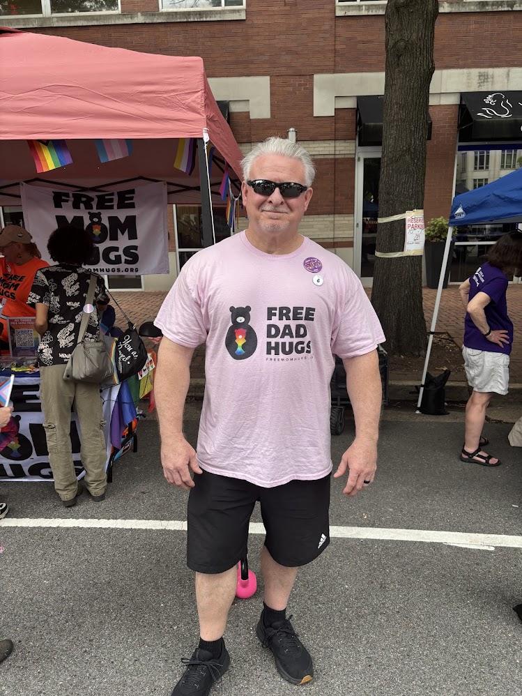 Person wearing pink "free dad hugs" t-shirt