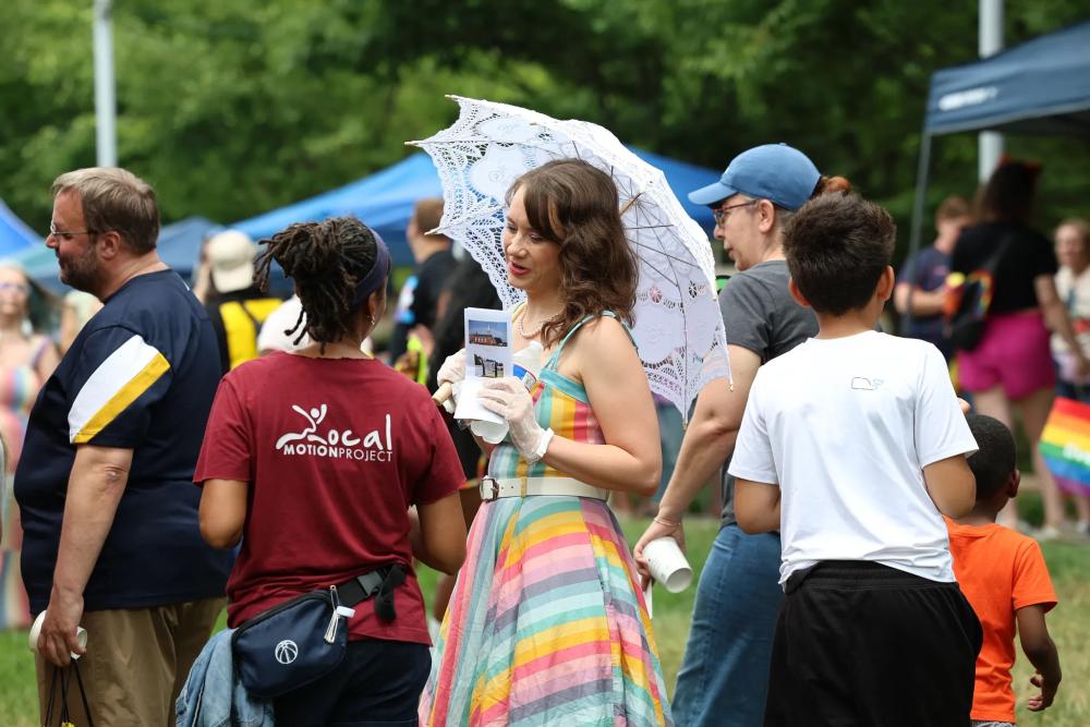 Person in rainbow dress holding parasol at Alexandria Pride 2026