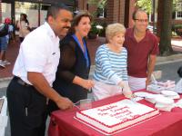 City of Alexandria representatives pose for a photograph at the 2019 Festival while cutting a cake.  From left to right: Acting Fire Chief Corey A. Smedley, Councilmember Amy Jackson, Councilmember Redella S. "Del" Pepper, Mayor Justin M. Wilson.