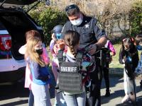deputy helps a student try on protective equipment
