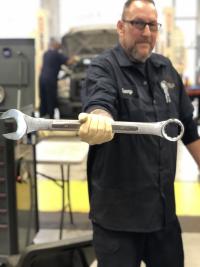 A Fleet Management expert techinician holds a wrench used to perform vehicle service.