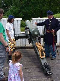 Reenactor shows a cannon to a family at Civil War Camp Day