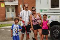 Little boy in a Sonic outfit, a dad in a white shirt, a mom in a pink tank top, and a little girl in a pink top are all smiles