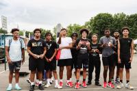 A group of teenage boys mostly dressed in black, some are in white pose for the camera