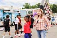 A group of boys walking away, a little boy in red standing next to a woman in a checkered long-sleeve top