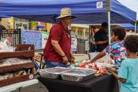 Kids buying snacks from man with a hat and red shirt
