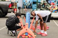 A boy in black with a black backpack and a boy in white are playing lawn-size Connect 4