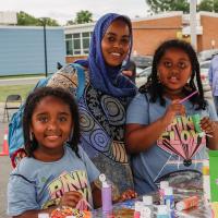 A mother with her two daughters smile as they paint