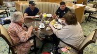 deputy sitting at small dining table with three senior citizens enjoying lunch
