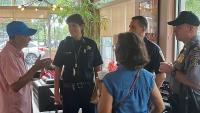 two community members speaking with three law enforcement officers inside a coffee shop