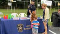 deputy behind a table at a community event speaking with woman and children on the other side of the table