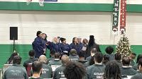 choir members in robes singing and about 20 inmates seated and listening