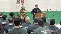 sheriff speaking at podium in jail with inmates seated in front and Christmas decorations in the background