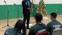 man playing a saxophone with three inmates in jumpsuits listening