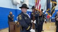 deputy at podium singing with honor guard presenting flags